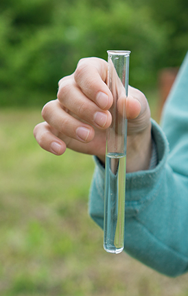 Water Purity Test, female hand holding liquid in laboratory glassware